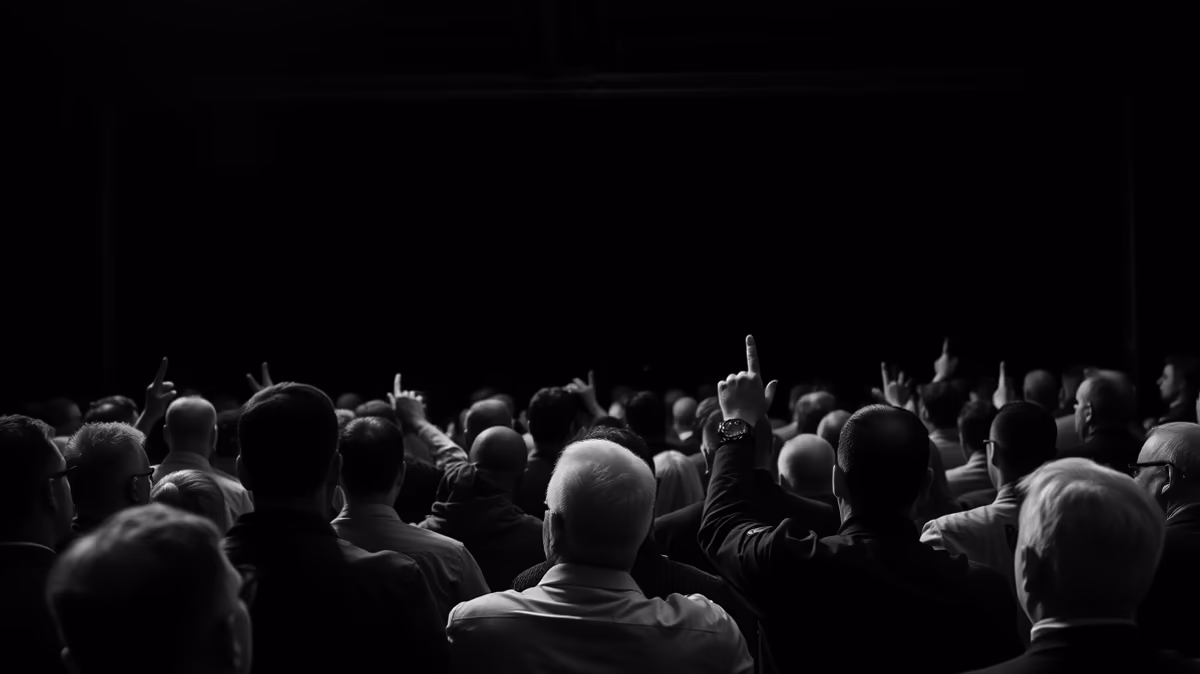 A crowd of people with their hands raised, silhouetted against a dark background.